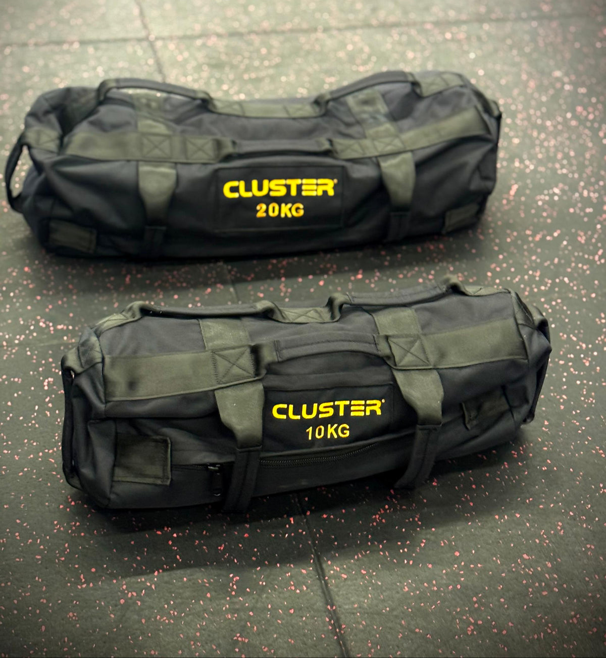 Two black sandbags with yellow text on a gray floor.