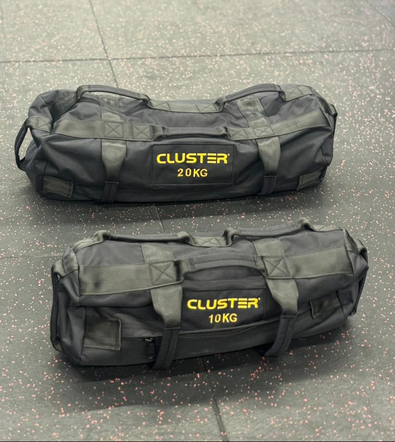 Two blackCluster bags with yellow text on a concrete surface