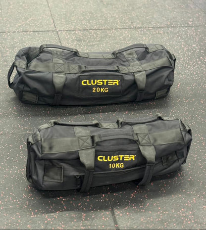 Two blackCluster bags with yellow text on a concrete surface